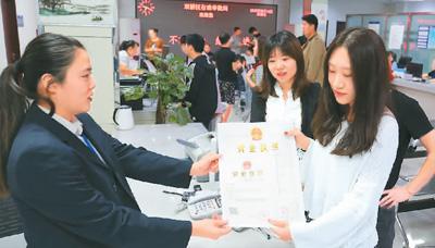 河北省承德市網(wǎng)絡(luò)代購經(jīng)營者陳晨(右)從工作人員手中接過帶有統(tǒng)一社會信用代碼的營業(yè)執(zhí)照。 劉環(huán)宇攝(人民圖片)